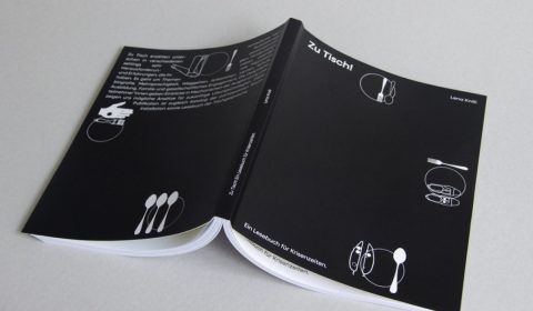 Ein aufgeschlagenes Buch liegt mit dem schwarzen Rücken nach oben